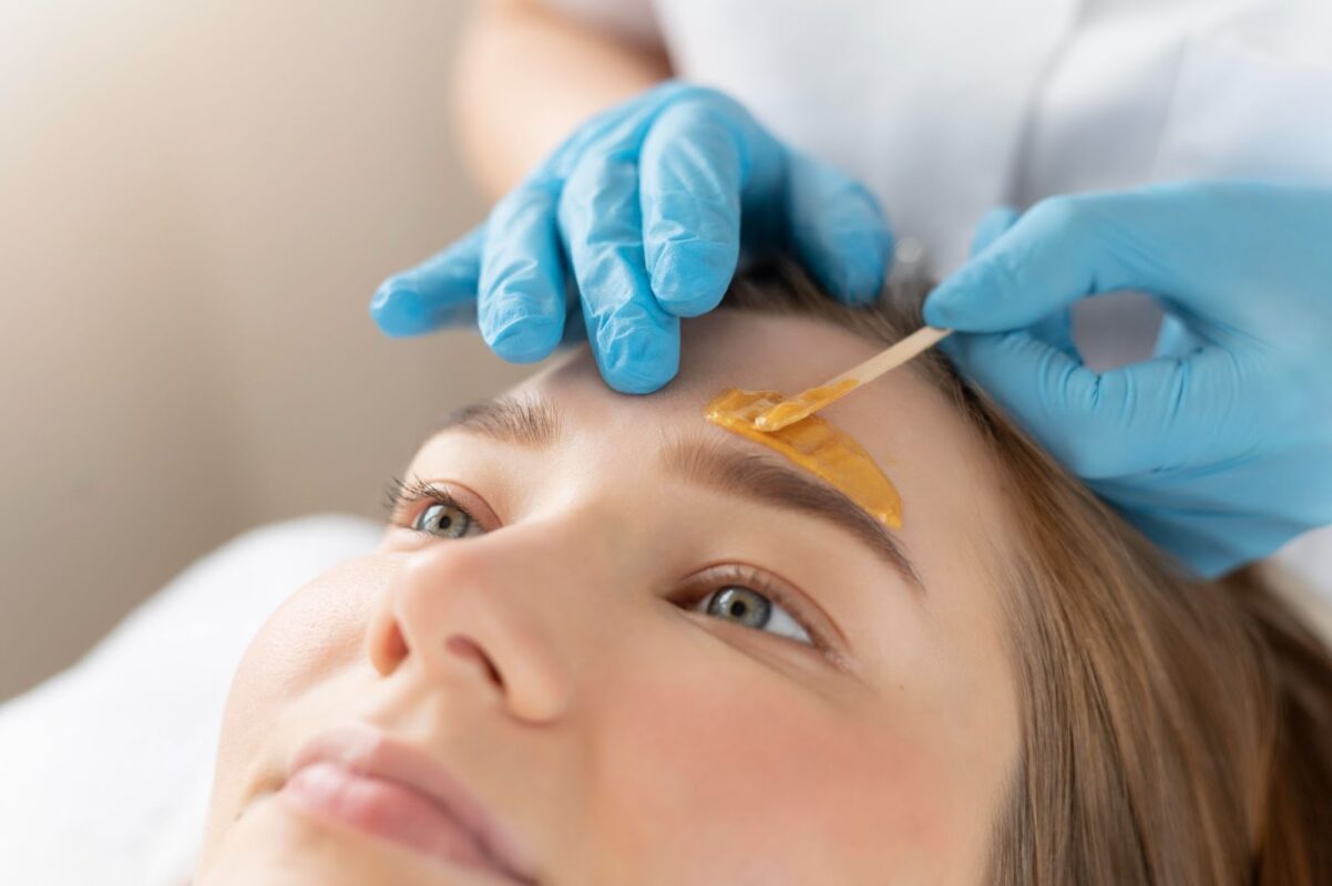 Esthetician waxing client’s eyebrows